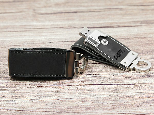 Leder-USB-Stick in Schwarz mit silbernem Metallverschluss und Platz für individuelles Logo. Praktisch und elegant.
