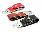 Drei stilvolle USB-Sticks mit Lederhülle in Rot, Braun und Schwarz, ideal für individuelles Branding und Werbung.