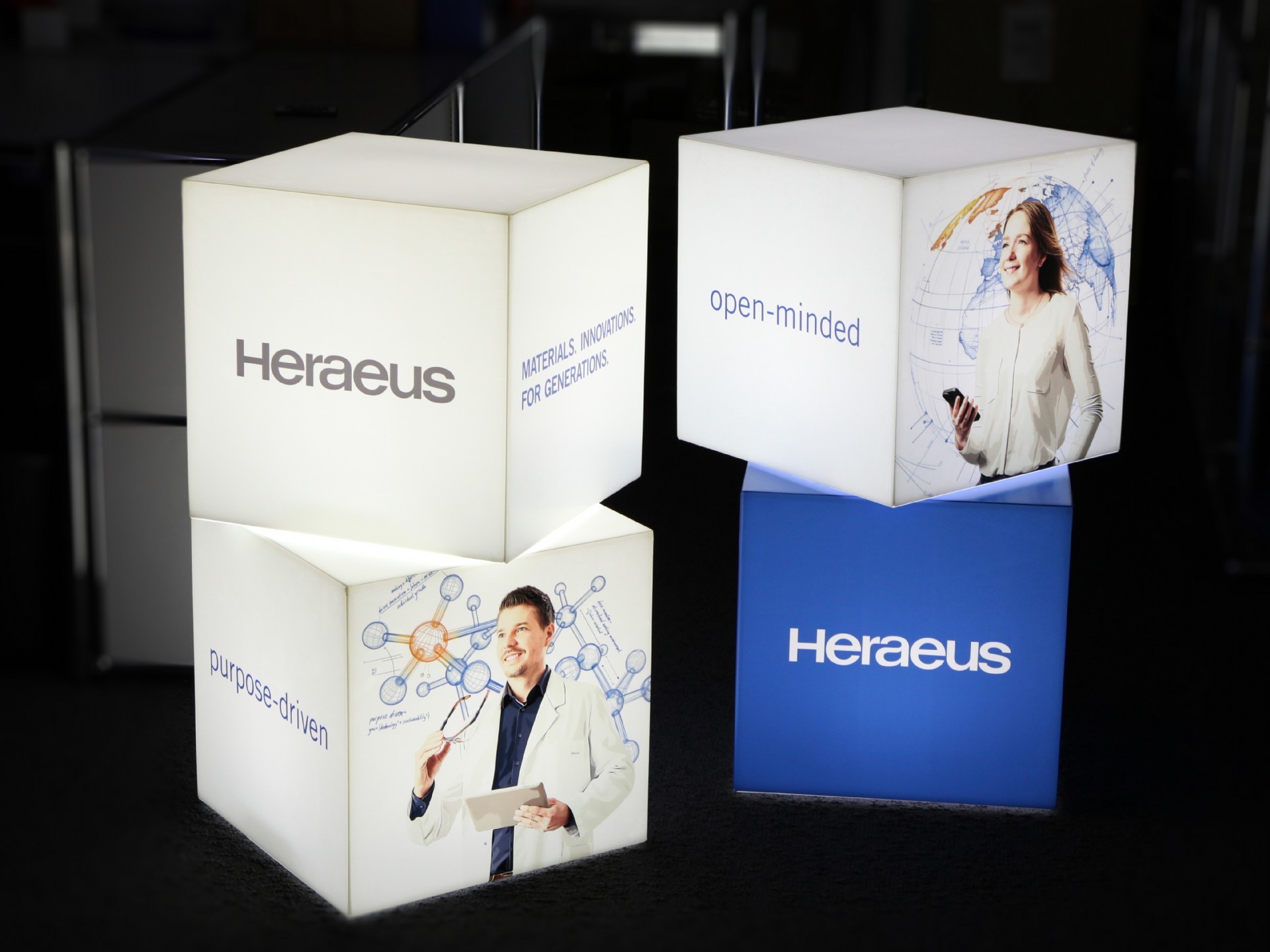 Leuchtende Werbewürfel mit dem Logo von Heraeus und Bildern, die Innovationsgeist und Offenheit repräsentieren.