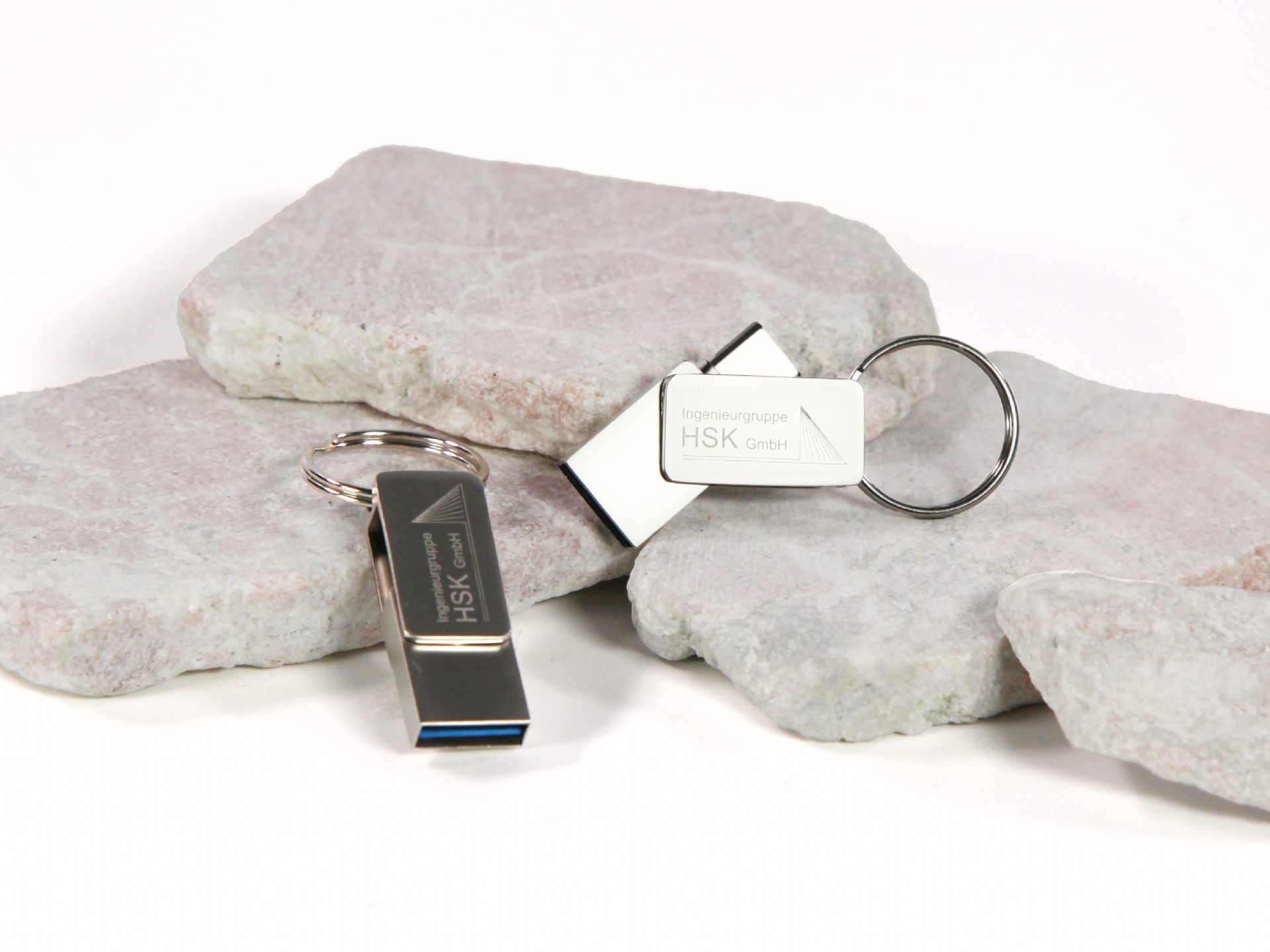 USB-Sticks in modernem Design mit Platz für individuelle Logo-Gestaltung, präsentiert auf grauen Steinplatten.